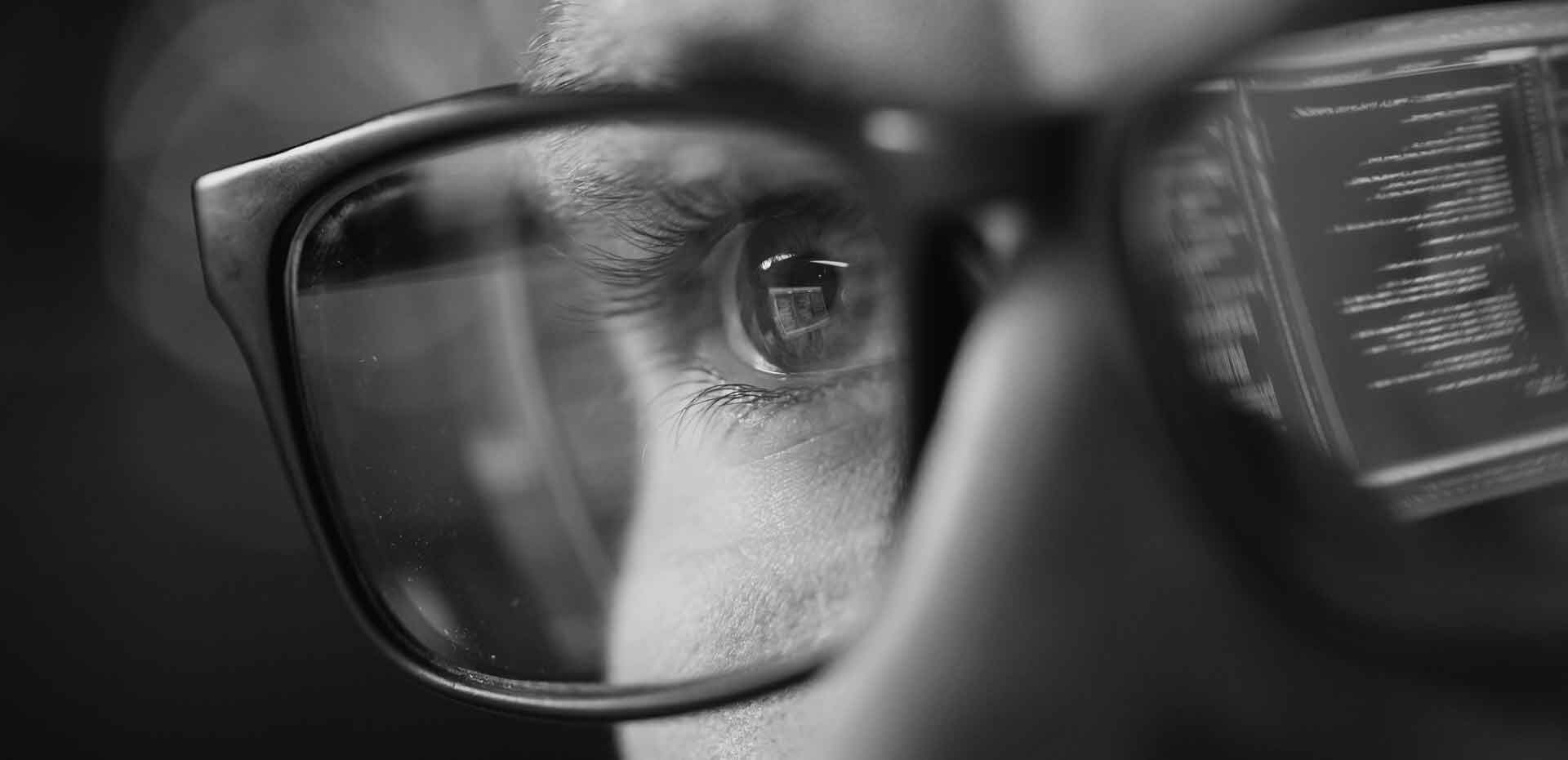 Close-up of a developer's eye behind glasses, with lines of code reflected in the lens